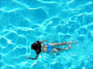 Young woman swimming in beautiful clear blue swimming pool