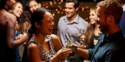 People enjoying drinks and laughing at a lively social gathering.