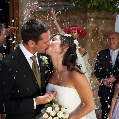 Bride and groom sharing a kiss amidst wedding confetti.