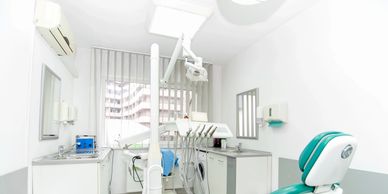Clínica dental blanca y luminosa con sillón verde.