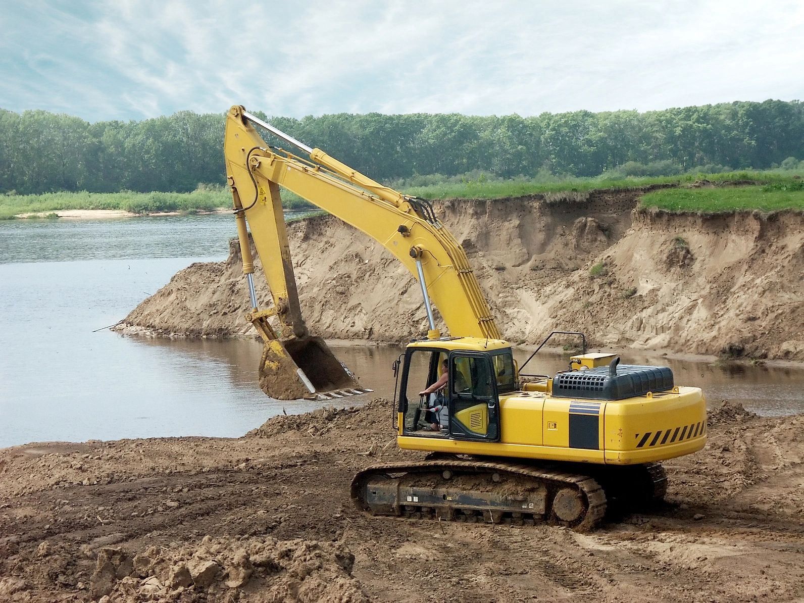An excavator digging out dirt for a stock tank