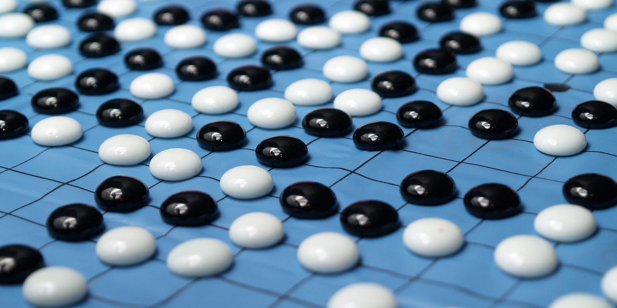 Black and white Go game stones on a blue board.