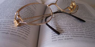 A pair of glasses resting on an open book with text in Turkish.