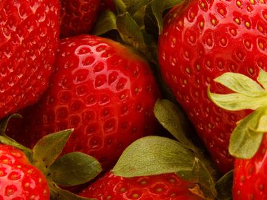 Close-up of fresh, ripe strawberries with green leaves.