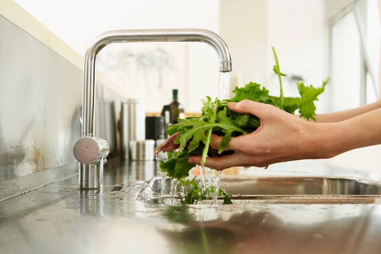 green vegetable leaves being washed in the sink
