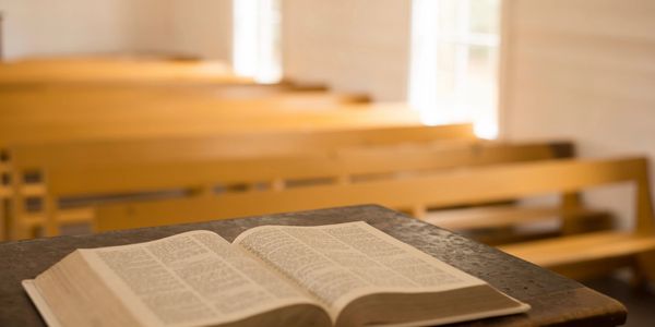 Photo of church pews with a Bible on a lectern in the foreground.