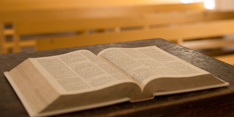 Open book on a wooden desk with blurred wooden background.