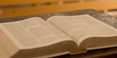 An open book resting on a wooden surface with blurred background.