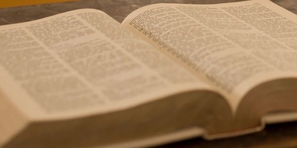 An open book with text on both pages, lying on a wooden surface.