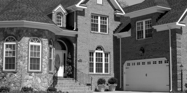 Elegant brick and stone house with a large garage and manicured landscaping.