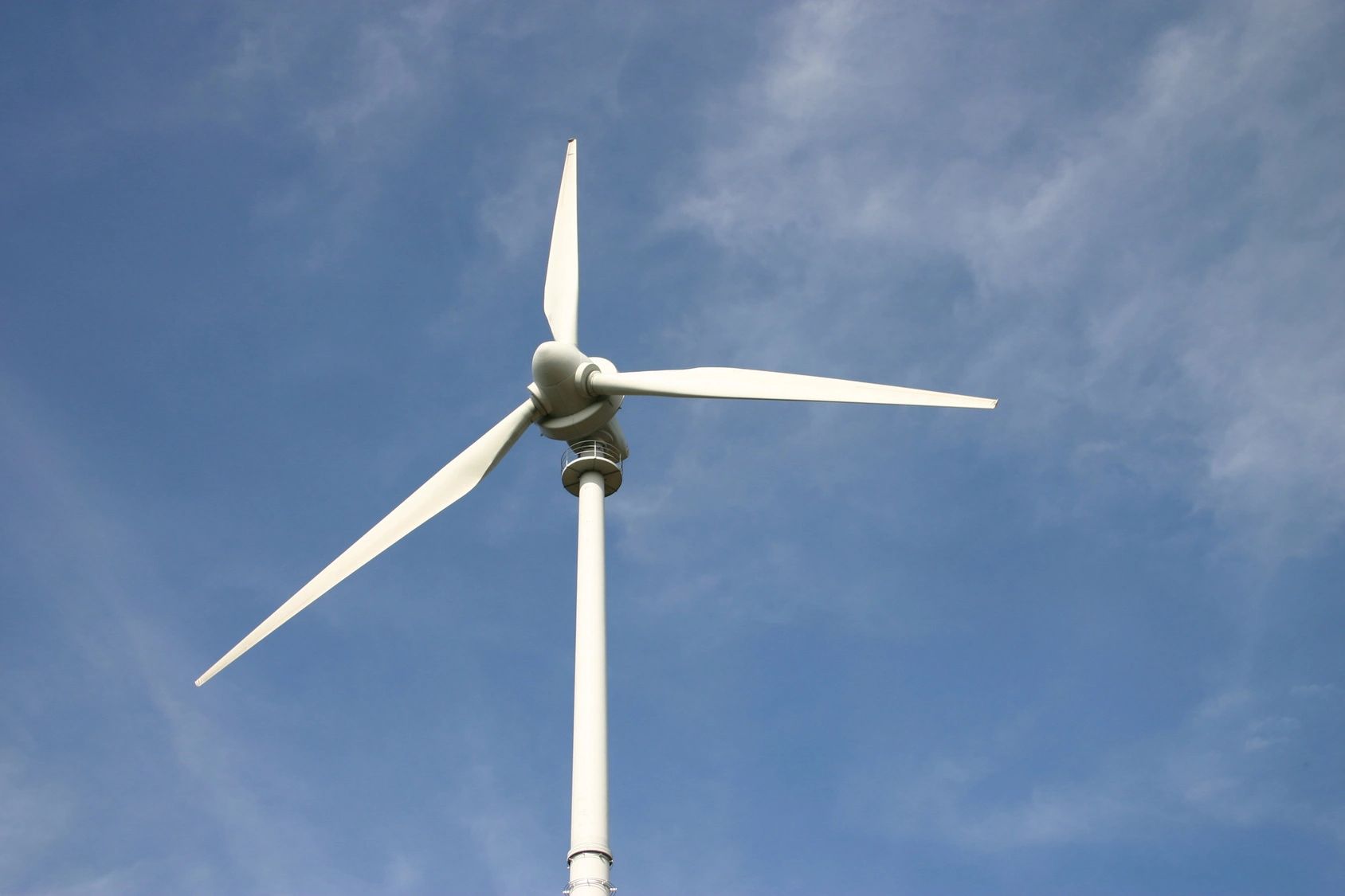 White wind turbine against a blue sky with light clouds.