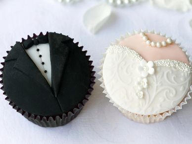 Wedding-themed cupcakes designed as a tuxedo and a bridal gown.