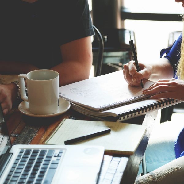 Woman writing in a notebook surrounded by colleagues.