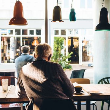 Two elderly men sitting in a cozy cafe by the window.