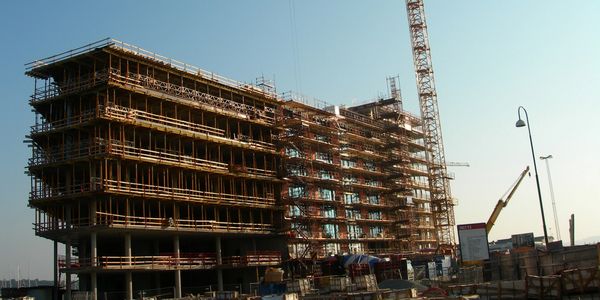 Large building under construction with scaffolding and a tall crane.