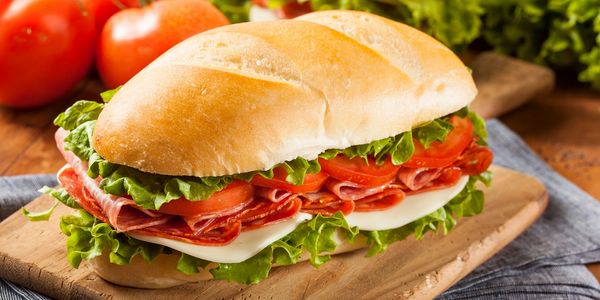 A delicious, Italian deli sandwich with ham, tomatoes, salad and mozzarella.