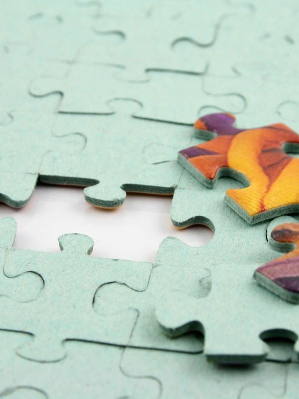 Two colorful puzzle pieces next to an empty spot in a light blue puzzle.