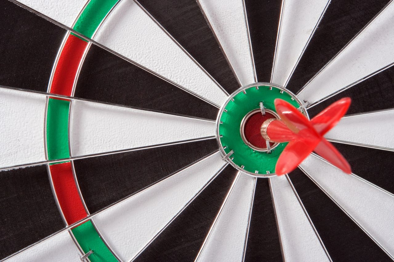 A red dart in the bullseye of a dart board.