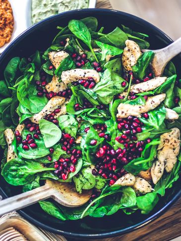 Fresh spinach salad with grilled chicken and pomegranate seeds.