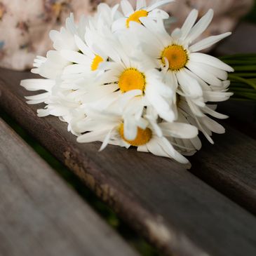 A bouquet of white daisies with yellow centers on a wooden surface.
