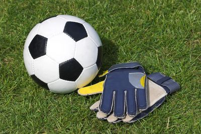 A Football and goalie gloves laying on grass.