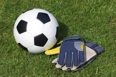 Soccer ball and goalie gloves on grass.