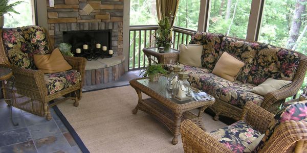 Screened in back porch with furniture and a fireplace.