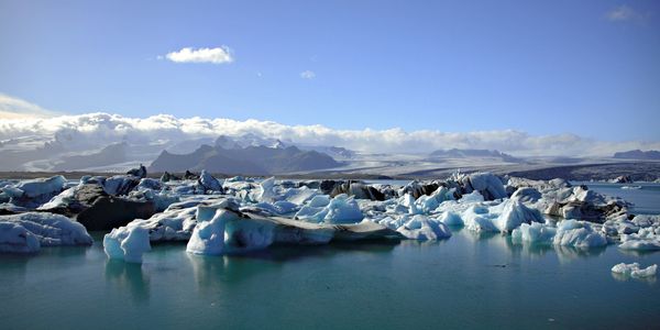 Glacier icebergs floating in a serene blue lake under a clear sky.