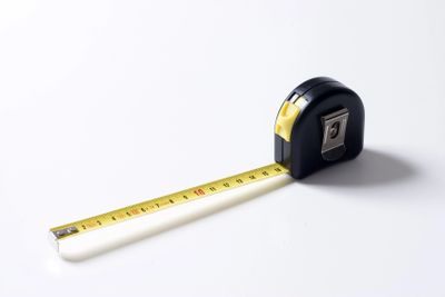 A black and yellow measuring tape extended on a white surface.