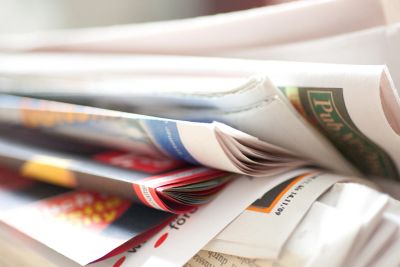 A close-up of folded newspapers and magazines stacked together.