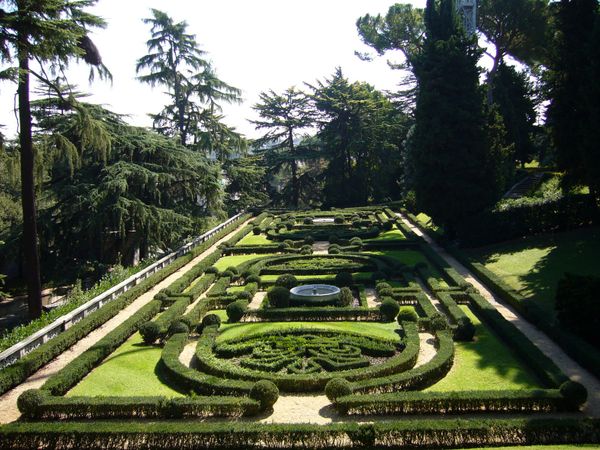 Symmetrical formal garden with manicured bushes and trees.
