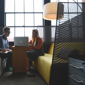 Two people working together on a laptop in a modern office.
