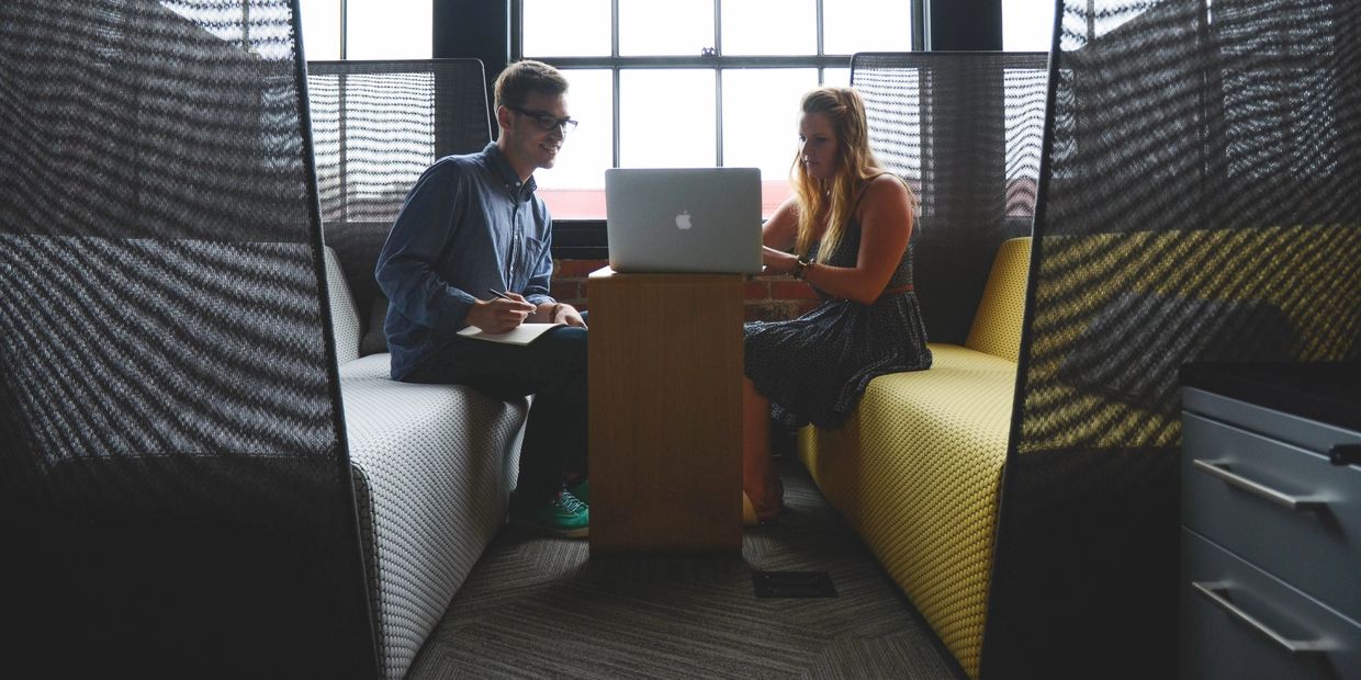 Two people sitting on a couch looking at a laptop.
