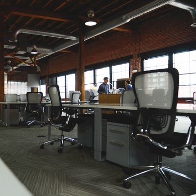Modern office space with empty chairs and a few people in the background.