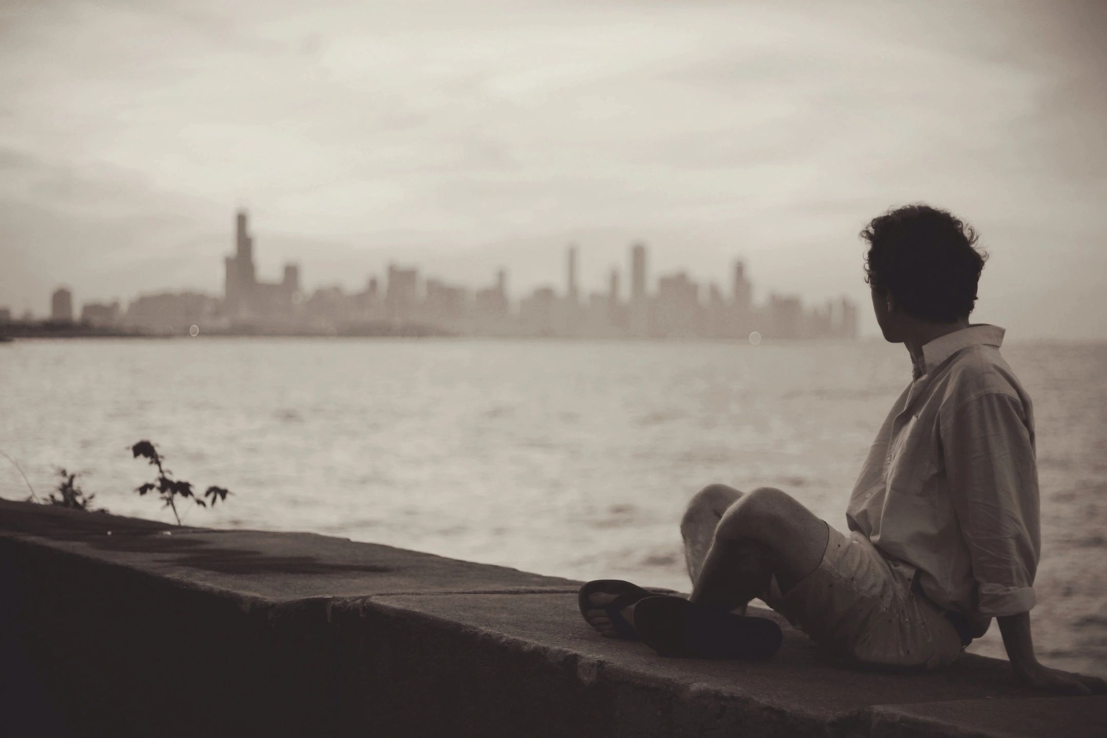 man sitting on wall look at the city skyline 