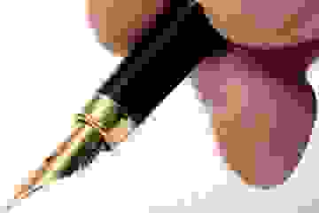 A hand holding a black and gold fountain pen.