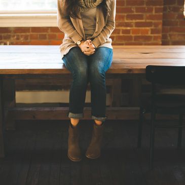 Woman sitting on the edge of a table with her hands folded in her lap