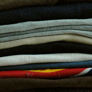 Stack of folded clothes in various colors and fabrics.