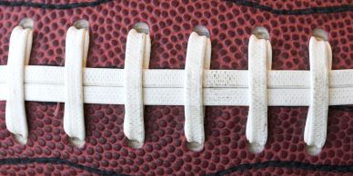 Close-up of an American football's laces on its textured surface.