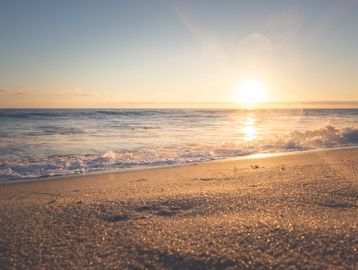 Sunset view over a sandy beach with gentle waves.
