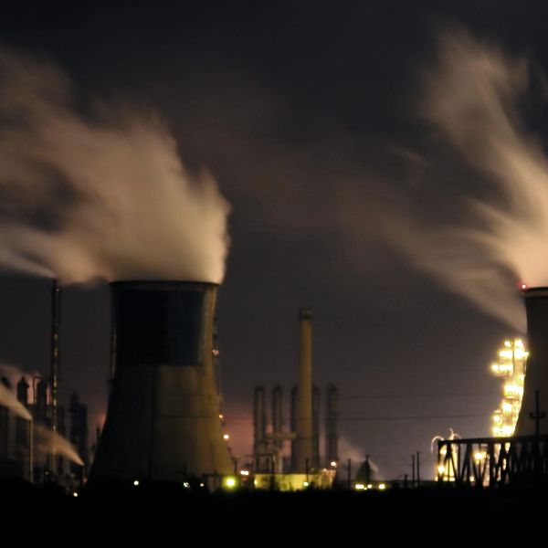 Industrial plant emitting smoke at night under a dark sky.