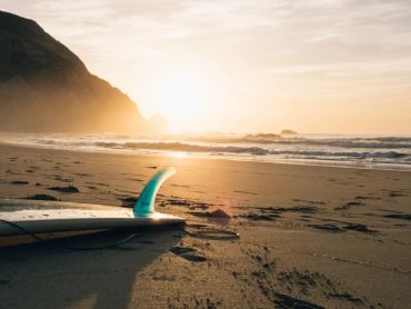 Surfboard on beach at sunset.