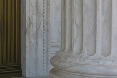 Close-up of a large marble column base with detailed fluting and ornate wall molding.
