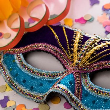 A colorful, decorated masquerade mask surrounded by confetti.
