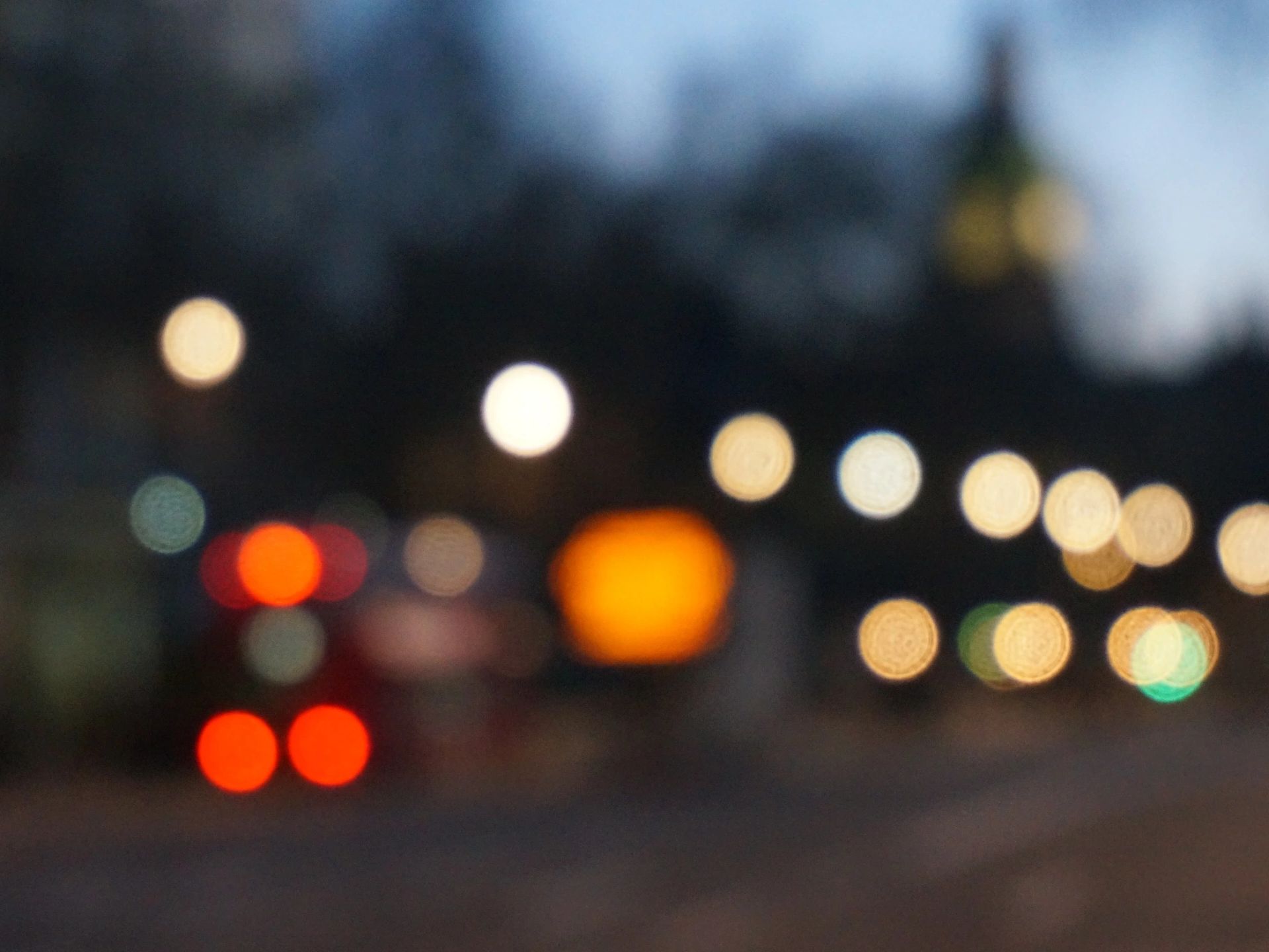 Blurred city lights and vehicles at dusk creating a bokeh effect.