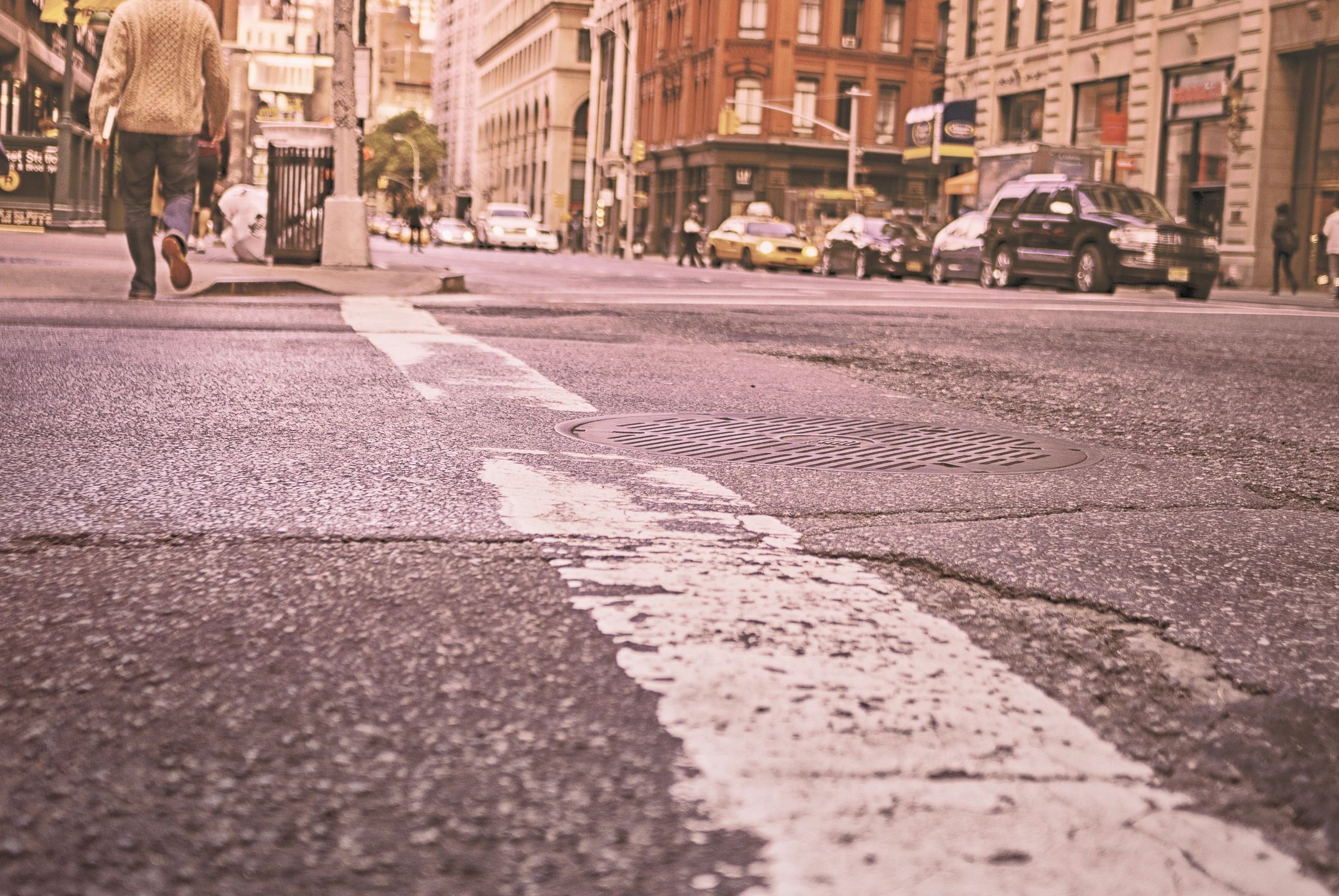 Low view of a metropolitan street and a man at the end of a cross walk. 