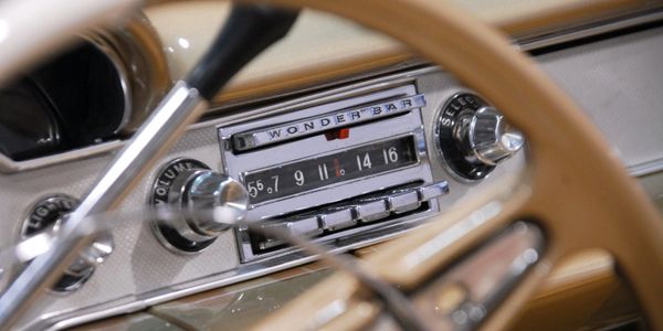 Close-up of a vintage car radio labeled 'Wonder Bar' behind a wooden steering wheel.