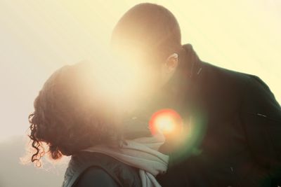 A couple sharing a kiss with sunlight creating a glowing effect.