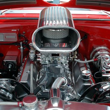 Highly polished, powerful engine with chrome components in a red car.