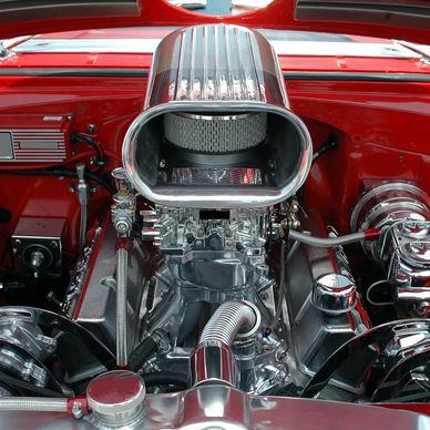 Highly polished car engine with red exterior and chrome details.